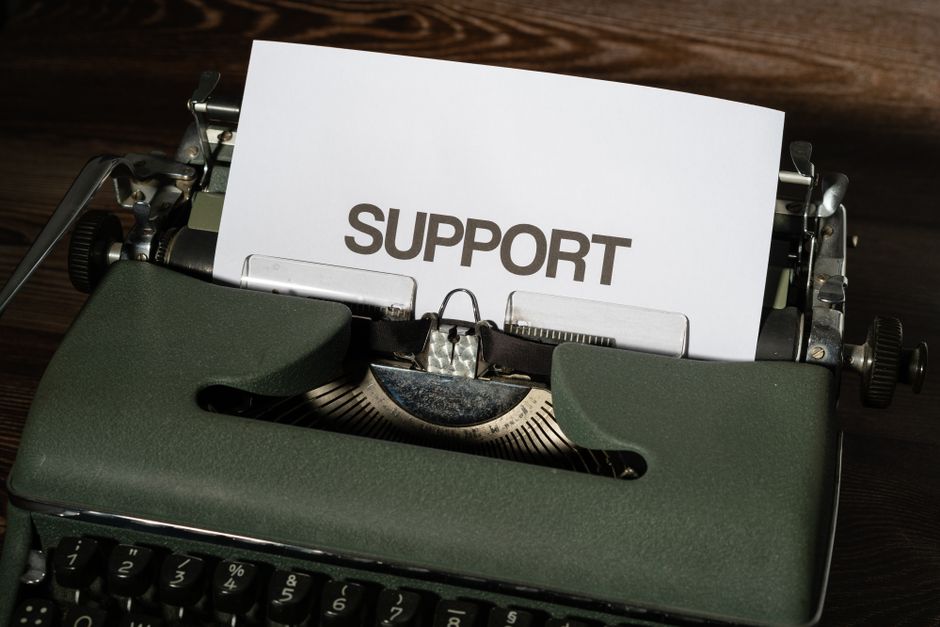 Close-up of vintage typewriter with 'SUPPORT' printed on paper, conveying assistance theme.